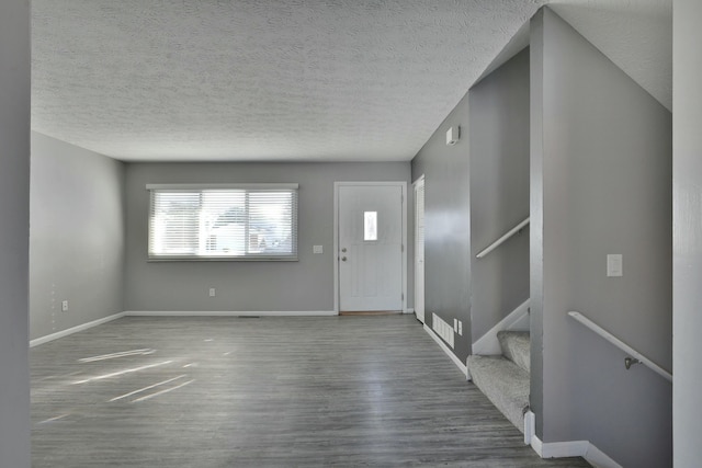 entryway featuring a textured ceiling, baseboards, and wood finished floors