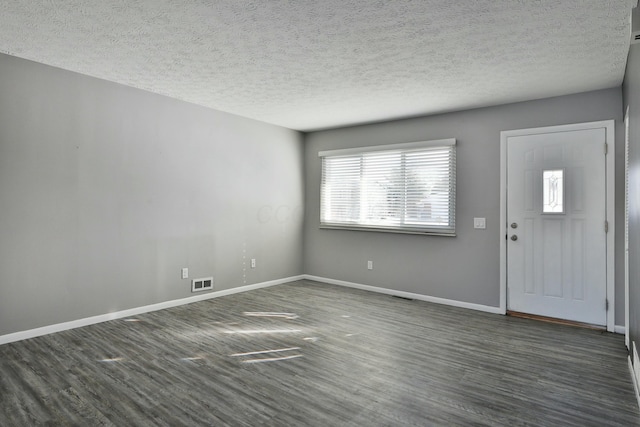 foyer with visible vents, baseboards, dark wood finished floors, and a textured ceiling