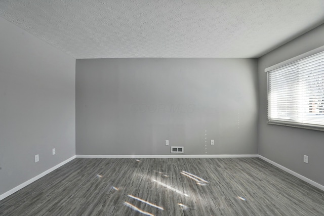 spare room with wood finished floors, visible vents, and baseboards