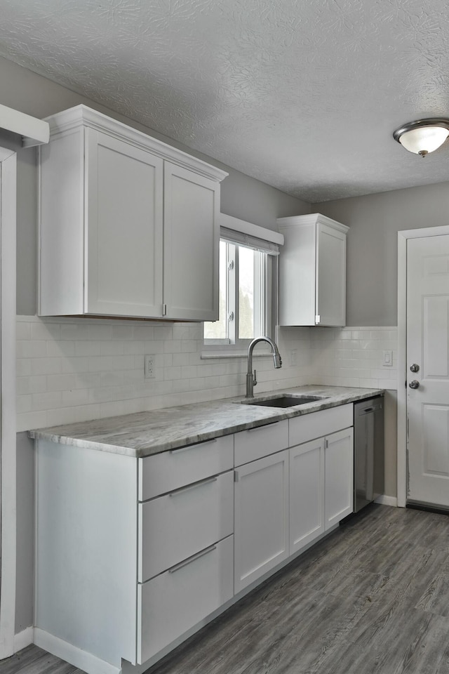 kitchen featuring decorative backsplash, dishwasher, dark wood-type flooring, white cabinetry, and a sink