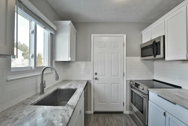 kitchen with appliances with stainless steel finishes, white cabinets, and a sink