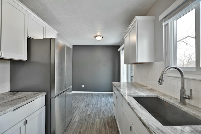 kitchen featuring a wealth of natural light, a sink, freestanding refrigerator, and white cabinetry