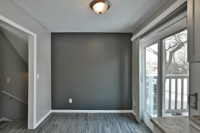 entryway with a textured ceiling, baseboards, and wood finished floors