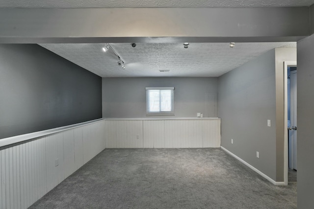 carpeted spare room featuring a wainscoted wall and a textured ceiling