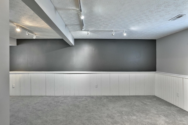 finished basement with a wainscoted wall, visible vents, a textured ceiling, and carpet flooring