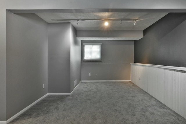 basement featuring rail lighting, visible vents, and carpet flooring