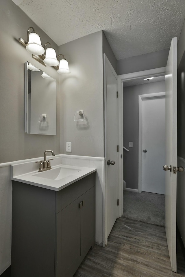 bathroom with wood finished floors, a textured ceiling, and vanity