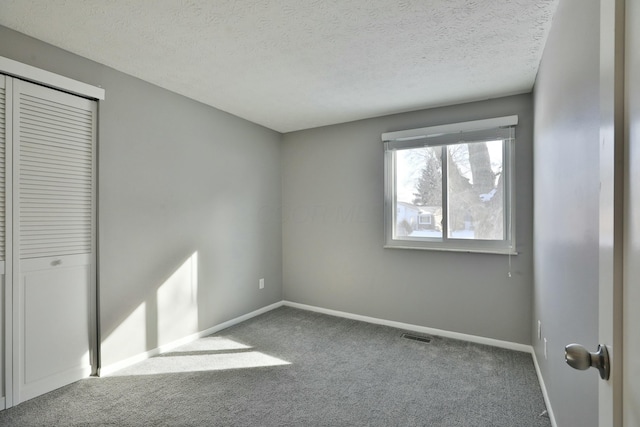 unfurnished bedroom featuring a textured ceiling, carpet, and baseboards