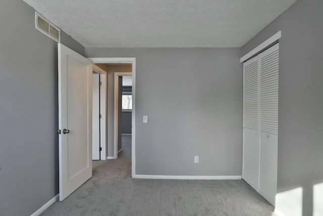 unfurnished bedroom with a closet, carpet, visible vents, and baseboards