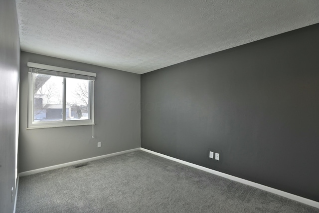 carpeted spare room featuring a textured ceiling, visible vents, and baseboards