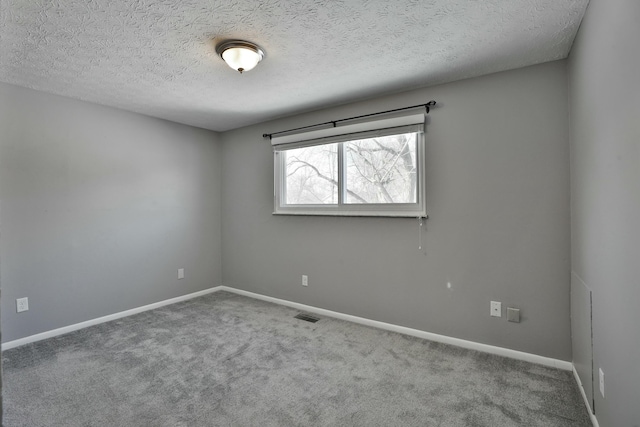 empty room featuring a textured ceiling, carpet flooring, visible vents, and baseboards