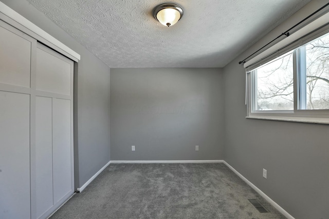 unfurnished bedroom featuring carpet floors, baseboards, visible vents, and a closet