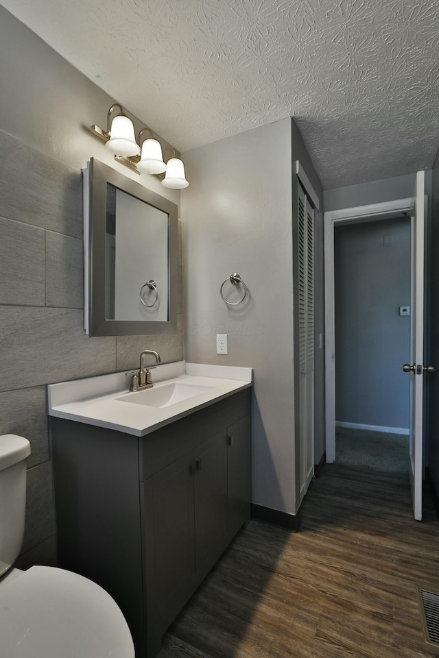 bathroom featuring visible vents, toilet, a textured ceiling, vanity, and wood finished floors