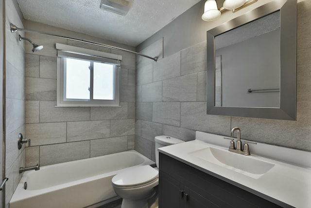 bathroom with tile walls, toilet, vanity, shower / tub combination, and a textured ceiling