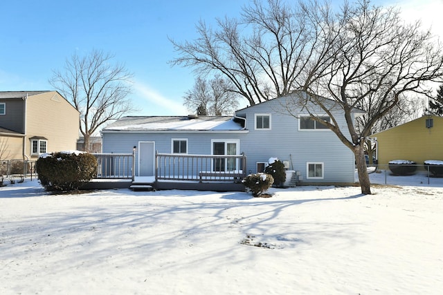 snow covered back of property featuring a wooden deck