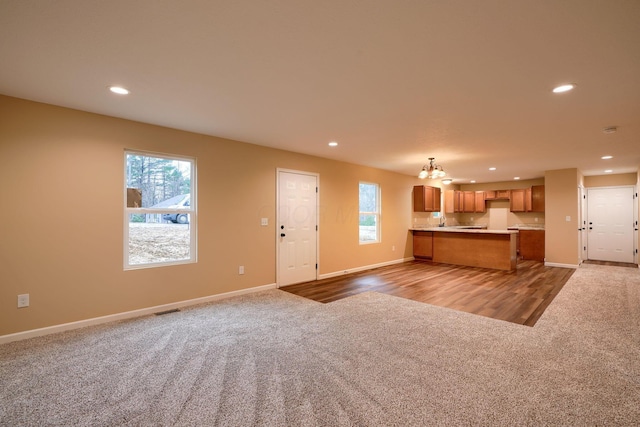 interior space featuring carpet, brown cabinets, recessed lighting, open floor plan, and a healthy amount of sunlight