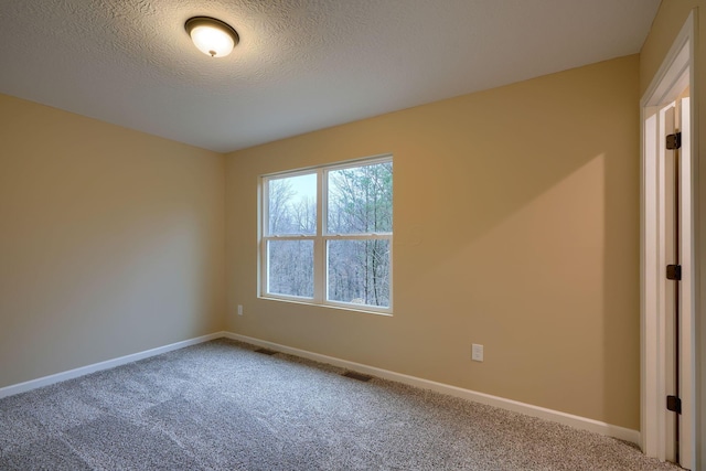 carpeted empty room featuring a textured ceiling, visible vents, and baseboards