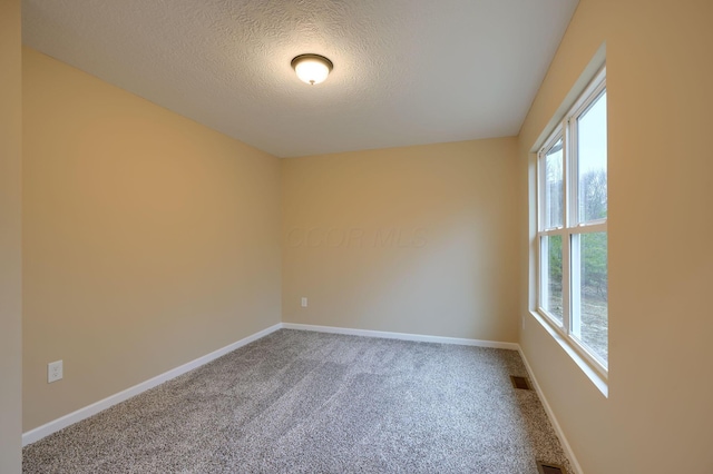 unfurnished room with baseboards, a textured ceiling, visible vents, and carpet flooring