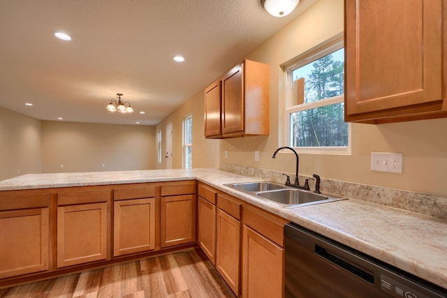 kitchen with light wood finished floors, dishwashing machine, a peninsula, light countertops, and a sink