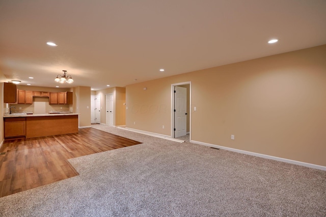 unfurnished living room with light carpet, baseboards, a sink, and recessed lighting