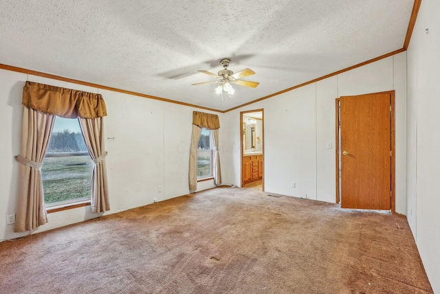 spare room with a textured ceiling, carpet floors, ceiling fan, and crown molding