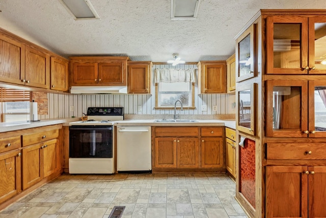 kitchen featuring electric stove, light countertops, stainless steel dishwasher, a sink, and under cabinet range hood