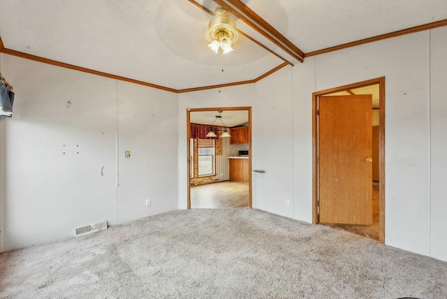 empty room featuring ceiling fan, lofted ceiling with beams, carpet flooring, visible vents, and crown molding