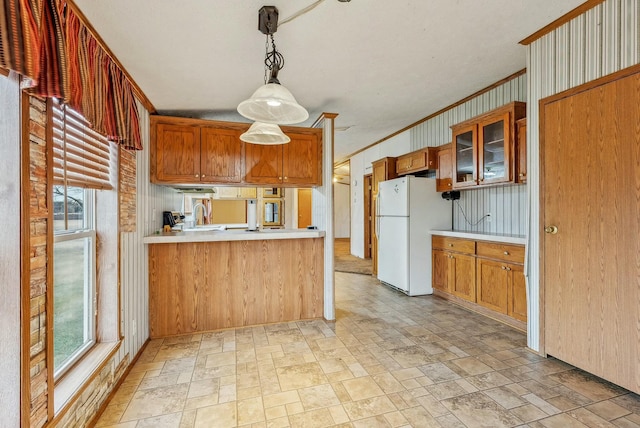 kitchen with light countertops, freestanding refrigerator, brown cabinets, stone finish flooring, and glass insert cabinets