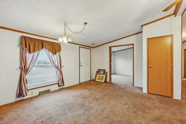 unfurnished room with a notable chandelier, visible vents, ornamental molding, and carpet flooring