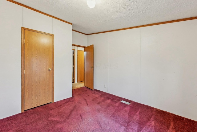 unfurnished bedroom featuring a textured ceiling, carpet floors, ornamental molding, and visible vents