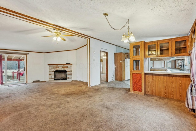 kitchen featuring brown cabinetry, freestanding refrigerator, a textured ceiling, carpet floors, and a sink