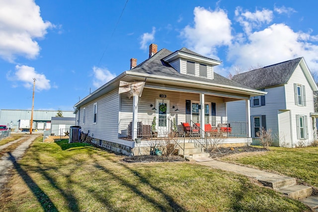 view of front of house with a chimney, a porch, and a front yard