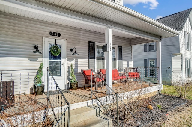 entrance to property with a porch and roof with shingles