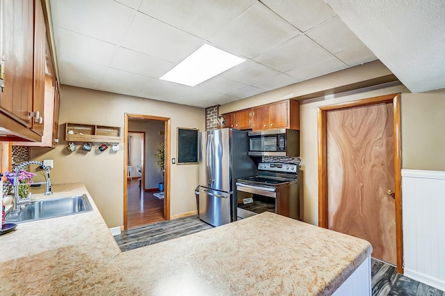 kitchen featuring stainless steel appliances, dark wood finished floors, a sink, and light countertops