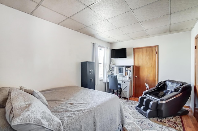 bedroom featuring a drop ceiling and wood finished floors