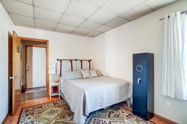 bedroom with a drop ceiling and wood finished floors