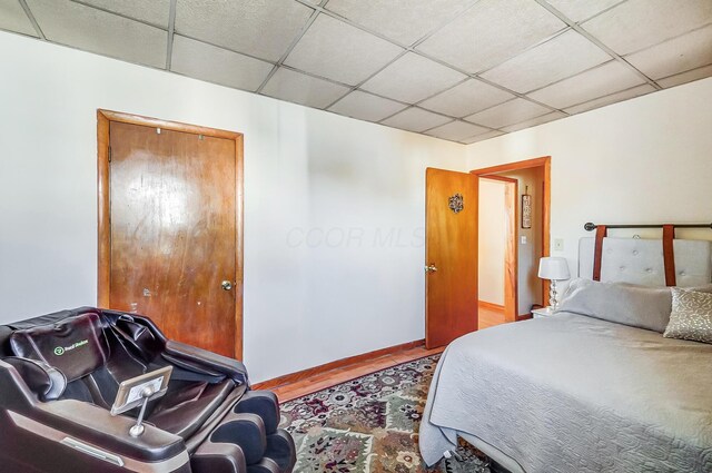 bedroom with a paneled ceiling and baseboards