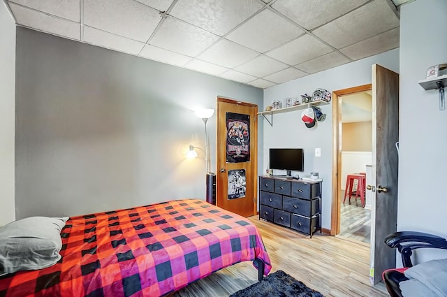 bedroom featuring a drop ceiling and light wood-style flooring