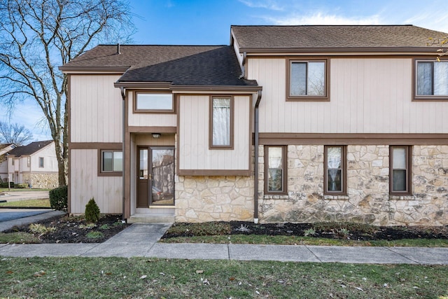 split level home with stone siding and roof with shingles