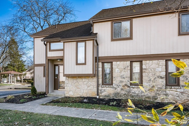 view of front of house featuring a shingled roof and stone siding