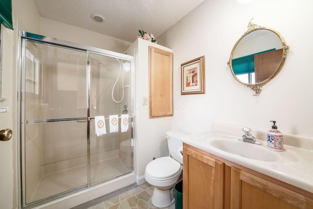 bathroom with a textured ceiling, vanity, toilet, and a shower stall