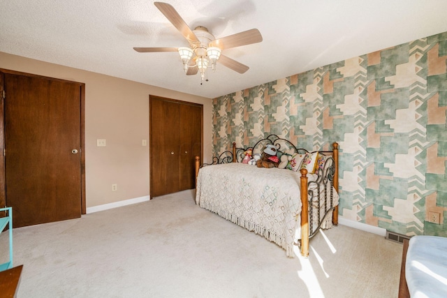 bedroom with wallpapered walls, visible vents, baseboards, carpet flooring, and a closet