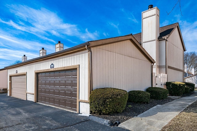 view of home's exterior featuring a chimney and community garages