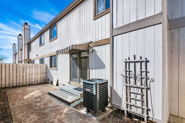 back of property with a patio, a chimney, entry steps, central AC, and fence