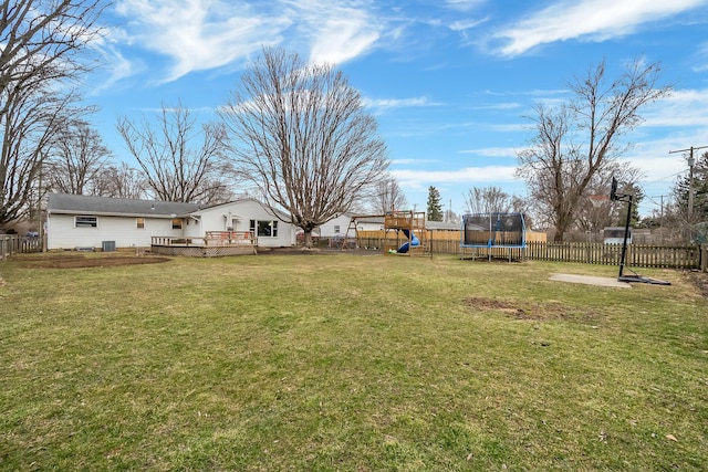 view of yard with a trampoline, a deck, a playground, and a fenced backyard