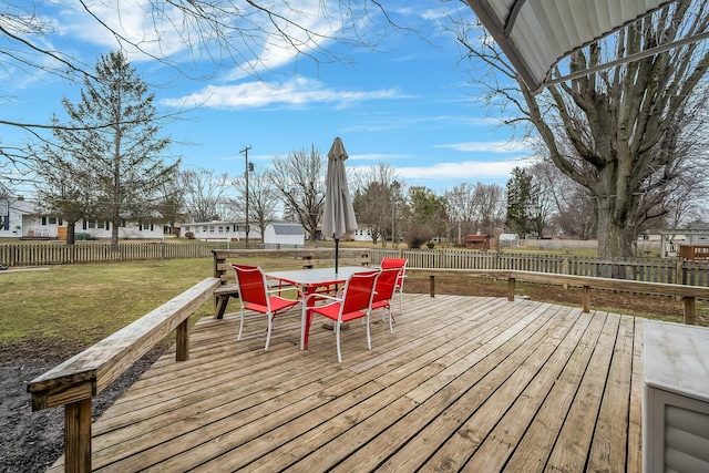 deck featuring outdoor dining area, a fenced backyard, and a yard