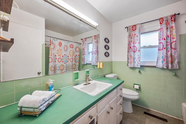 bathroom featuring tile patterned flooring, tile walls, toilet, a wainscoted wall, and visible vents
