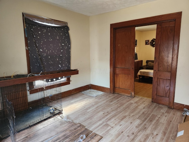 interior space with a textured ceiling, wood finished floors, and baseboards