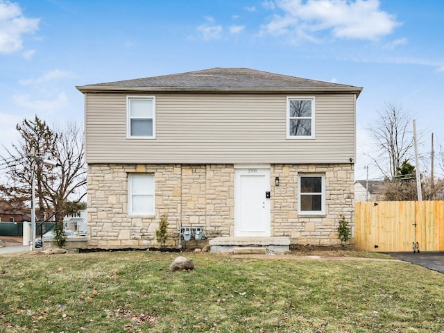 view of front of home featuring a front lawn, roof with shingles, and fence