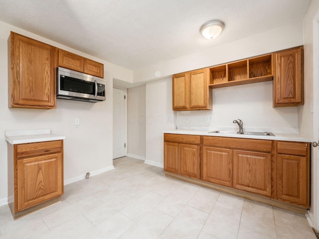 kitchen featuring brown cabinets, light countertops, stainless steel microwave, and a sink